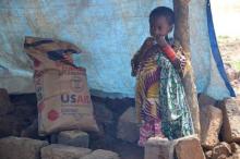 An internally displaced girl stands next to a bag of corn and soy flour provided by the World Food Program in Muhuya village in southeastern Democratic Republic of the Congo. PHOTO BY REUTERS/Habibou Bangre