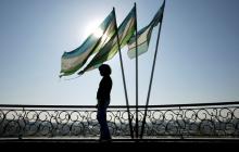 A girl is silhouetted against the sun standing next to Uzbek flags in Tashkent, Uzbekistan, November 5, 2005. PHOTO BY REUTERS/Shamil Zhumatov