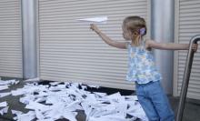 A girl launches a self-made paper plane outside the Dutch embassy as people gather to commemorate the victims of the Malaysia Airlines flight MH17 plane crash a year ago in Kiev, Ukraine, July 17, 2015. PHOTO BY REUTERS/Valentyn Ogirenko