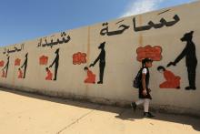 An Iraqi student walks past a school wall covered with drawings showing how Islamic State militants executed their prisoners in Mosul, Iraq, April 30, 2018. PHOTO BY REUTERS/Ari Jalal