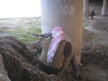 A masked Sunni Muslim gunman takes position with his weapon during clashes with Iraqi security forces outside the city of Falluja, 70 km (44 miles) west of Baghdad