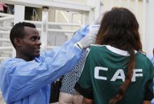 A health worker checks the temperature of a person wearing a Confederation of African Football (CAF) shirt at Malabo Stadium, ahead of their Group D soccer match against Cameroon in the African Cup of Nations, in Malabo, January 20, 2015. PHOTO BY REUTERS/Amr Abdallah Dalsh