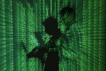 An illustration picture shows a projection of binary code on a man holding a laptop computer, in an office in Warsaw, June 24, 2013. PHOTO BY REUTERS/Kacper Pempel