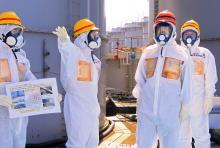 Japan's Prime Minister Shinzo Abe (2nd R), wearing protective suit and mask, is briefed about tanks containing radioactive water by Fukushima Daiichi nuclear power plant chief Akira Ono (2nd L)