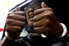 Detained Reuters journalist Wa Lone gestures to the media as he is escorted by police after a court hearing in Yangon, Myanmar, April 11, 2018. PHOTO BY REUTERS/Ann Wang