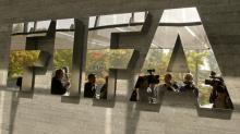 Journalists are reflected in a logo at the FIFA headquarters after a meeting of the executive committee in Zurich