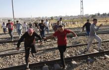 Turkish and Syrian Kurds run as Turkish security forces use tear gas to disperse them near the Mursitpinar border crossing on the Turkish-Syrian border, near the southeastern town of Suruc