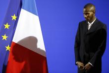 The shadow of Lassana Bathily (R), 24, is cast on the French flag during a ceremony to receive his citizenship papers at the Interior Ministry in Paris, January 20, 2015. PHOTO BY REUTERS/Charles Platiau