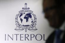 A man passes an Interpol logo during the handing over ceremony of the new premises for Interpol's Global Complex for Innovation, a research and development facility, in Singapore