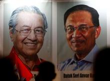 People pass posters of Malaysian Prime Minister Mahathir Mohamad and politician Anwar Ibrahim, who was granted a royal pardon, at a rally in Kuala Lumpur, Malaysia, May 16, 2018. PHOTO BY REUTERS/Lai Seng Sin
