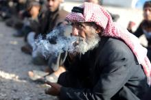 A displaced Iraqi man smokes a cigarette as he waits to enter Hammam al-Alil camp, south of Mosul, Iraq, April 8, 2017. PHOTO BY REUTERS/Andres Martinez Casares