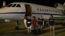 Medhanie Yehdego Mered (2nd L), 35, with Italian policemen as they land at Palermo airport, Italy, following his arrest in Khartoum, Sudan, May 24. PHOTO BY REUTERS/Italian Police Department