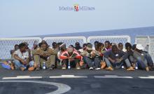 Migrants sit in a boat during a rescue operation by Italian navy ship Cigala Fulgosi off the coast of the south of the Italian island of Sicily in this October 30, 2013 picture provided by the Italian Marina Militare