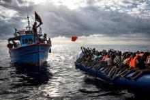 Libyan fishermen throw a life jacket at a rubber boat full of migrants. Migrants are very often not given any life jackets or means of communication by their smugglersm. PHOTO BY REUTERS/Mathieu Willcocks/MOAS.eu