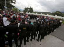 Guatemalan police officers watch as Honduran migrants, part of a caravan trying to reach the U.S., arrive in Esquipulas city in Guatemala, October 15, 2018. PHOTO BY REUTERS/Jorge Cabrera