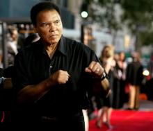 Boxing legend Muhammad Ali (R) jabs at photographers while arriving at the Orpheum Theatre for the premiere of the film "Collateral" in Los Angeles, August 2, 2004. PHOTO BY REUTERS/Robert Galbraith
