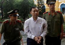 Nguyen Bac Truyen (C), 39, is escorted by security personnel as he arrives at a court in Ho Chi Minh city, Vietnam, May 10, 2007. PHOTO BY REUTERS/Kham
