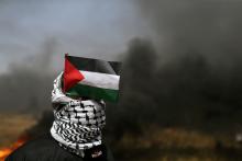 A demonstrator with a Palestinian flag looks on during clashes with Israeli troops at the Israel-Gaza border at a protest demanding the right to return to their homeland, in the southern Gaza Strip, April 6, 2018. PHOTO BY REUTERS/Ibraheem Abu Mustafa