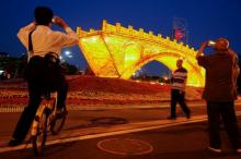 People take pictures of the "Golden Bridge on Silk Road" installation by artist Shuyong, set up ahead of the Belt and Road Forum in Beijing, China, May 10, 2017. PHOTO BY REUTERS/Thomas Peter