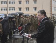 Ukrainian President Petro Poroshenko (R) delivers a speech in the rain during the ceremony of presenting new apartment certificates to local residents, including servicemen of the Ukrainian armed forces, Ukraine November 20, 2017. PHOTO BY REUTERS/Mykola Lazarenko