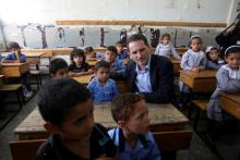 Pierre Krahenbuhl, United Nations Relief and Works Agency (UNRWA) Commissioner-General, sits with Palestinian students inside a classroom as he visits a United Nations-run school on the first day of a new school year in Khan Younis in the southern Gaza Strip