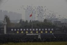 Pigeons fly above a Chinese flag flown at half-staff as people attend a ceremony to mark the second national memorial day for the Nanjing Massacre, at the Nanjing Massacre Museum in Nanjing, Jiangsu province, China, December 13, 2015. PHOTO BY REUTERS/China Daily