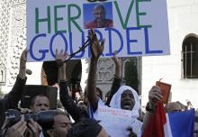 A man holds a placard which reads "Homage to Herve Gourdel", a French mountain guide who was beheaded by an Algerian Islamist group, during a gathering of Muslims in front of the Paris Mosque after Friday prayers