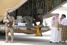 A Saudi soldier stands guard as servicemen on a Saudi military cargo plane prepare to unload aid at the international airport of Yemen's southern port city of Aden, July 24, 2015. PHOTO BY REUTERS/Faisal Al Nasser