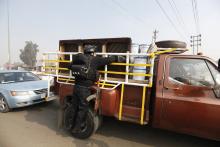 A police officer searches a vehicle at a checkpoint as security increases after a bomb attack, at Abu Ghraib district in west of Baghdad