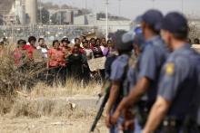 Police look on as women carry placards in protest against the killing of miners by the South African police on Thursday, outside a South African mine in Rustenburg, 100 km (62 miles) northwest of Johannesburg. PHOTO BY REUTERS/Siphiwe Sibeko