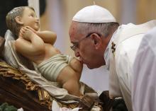 Pope Francis kisses the statue of baby Jesus as he arrives to lead the New Year mass in Saint Peter's Basilica at the Vatican, January 1, 2015. PHOTO BY REUTERS/Alessandro Bianchi