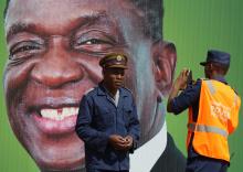 Police officers take photos in front of President Emmerson Mnangagwa's campaign poster in Harare, Zimbabwe, May 4, 2018. PHOTO BY REUTERS/Philimon Bulawayo