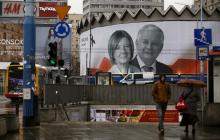 People walk in front of a giant picture of late Polish president Lech Kaczynski and his wife Maria, who died six years ago when a Polish government plane crashed in Smolensk, Russia, hanging on a building in the centre of Warsaw, Poland, April 10, 2016. PHOTO BY REUTERS/Kacper Pempel