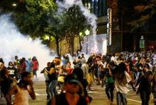 People run from flash-bang grenades in uptown Charlotte, NC during a protest of the police shooting of Keith Scott, in Charlotte, North Carolina, U.S., September 21, 2016. PHOTO BY REUTERS/Jason Miczek