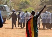 An opposition supporter faces police officers during a protest in Harare, Zimbabwe, August 26,2016. PHOTO BY REUTERS/Philimon Bulawayo