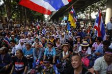Anti-government protesters sit on the road outside the national police headquarters where they protest in Bangkok
