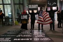 Protesters hold signs in opposition to U.S. President Donald Trump's ban on immigration and travel outside Terminal 4 at JFK airport in Queens, New York City, New York, U.S., January 29, 2017. PHOTO BY REUTERS/Joe Penney