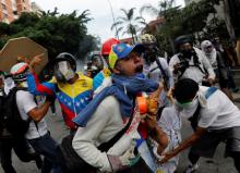 An injured opposition supporter is helped by others while clashing with riot police during a rally against President Nicolas Maduro in Caracas, Venezuela, May 3, 2017. PHOTO BY REUTERS/Carlos Garcia Rawlins
