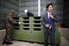 A reporter prepare a news report as South Korean soldiers dismantle loudspeakers that were set up for propaganda broadcasts near the demilitarized zone separating the two Koreas in Paju, South Korea, May 1, 2018. PHOTO BY REUTERS/Kim Hong-Ji