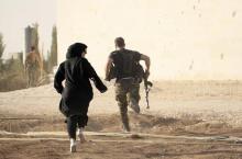 A woman reporter runs with a rebel fighter to avoid snipers at the frontline against the Islamic State fighters in Aleppo's northern countryside, October 10, 2014. PHOTO BY REUTERS/Jalal Al-Mamo