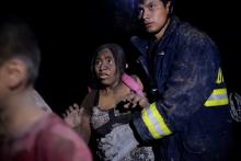 A rescue worker helps a woman covered with ash after Fuego volcano erupted violently in El Rodeo, Guatemala, June 3, 2018. PHOTO BY REUTERS/Fabricio Alonzo