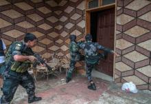 A joint group of police and military forces kick a door while conducting a house to house search. PHOTO BY REUTERS/Stringer