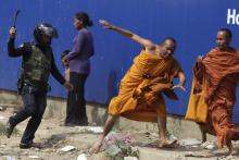 A security guard chases away Buddhist monks from a camp occupied by anti-government demonstrators in Phnom Penh