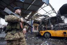 A member of the armed forces of the separatist self-proclaimed Donetsk People's Republic stands guard near a destroyed vehicle at a bus station after shelling in Donetsk, February 11, 2015. PHOTO BY REUTERS/Maxim Shemetov