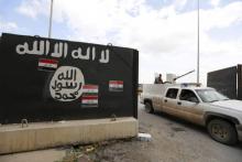 Iraqi security forces ride a vehicle past a wall painted with the black flag commonly used by Islamic State militants, near former Iraqi president Saddam Hussein's palace in Tikrit, April 1, 2015. PHOTO BY REUTERS/Thaier Al-Sudani