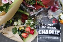 A sign which reads in French,"We are Charlie. Freedom of Expression" is placed on flowers as people continue to pay tribute to the shooting victims in front of the offices of the weekly satirical newspaper Charlie Hebdo in Paris, January 10, 2015. PHOTO BY REUTERS/Pascal Rossignol