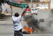 A man carries a street sign as opposition party supporters clash with police in Harare, Zimbabwe, August 26,2016. PHOTO BY REUTERS/Philimon Bulawayo