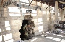 A Syrian army soldier loyal to Syria's President Bashar al-Assad walks through a hole in a wall in the old city of Aleppo