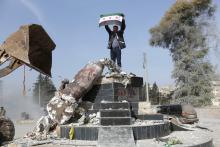Turkish-backed Free Syrian Army member holds a flag as they pull down Kurdish statue in the center of Afrin, Syria, March 18, 2018. PHOTO BY REUTERS/Khalil Ashawi