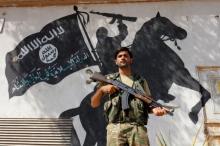 A member of Turkish-backed Free Syrian Army (FSA), seen with a mural of the Islamic State in the background, stands guard in front of a building in the border town of Jarablus, Syria, August 31, 2016. PHOTO BY REUTERS/Umit Bektas